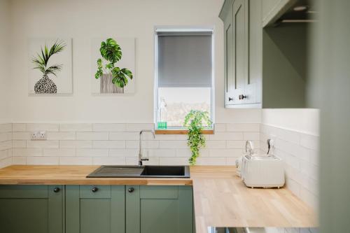 a kitchen with green cabinets and a sink at Gatekeepers Cottage - Idyllic 4 Bed Rural Escape! in Cropthorne
