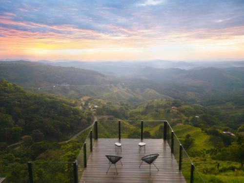 a wooden boardwalk with two chairs on top of a mountain at Amalú Luxury View Cabins in Monteverde Costa Rica