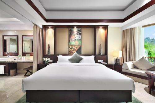 a bedroom with a large white bed and a bathroom at 广悦华阳朔河畔酒店 in Gaotian