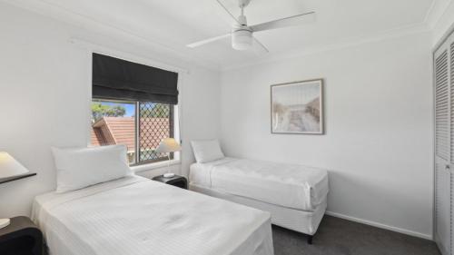a white room with two beds and a window at Barefoot On First - Pool, Beach, Family - Friendly in Sawtell