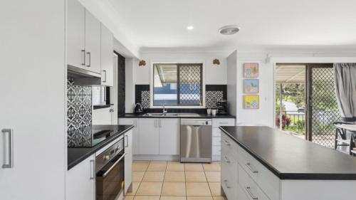 a kitchen with white cabinets and black counter tops at Barefoot On First - Pool, Beach, Family - Friendly in Sawtell