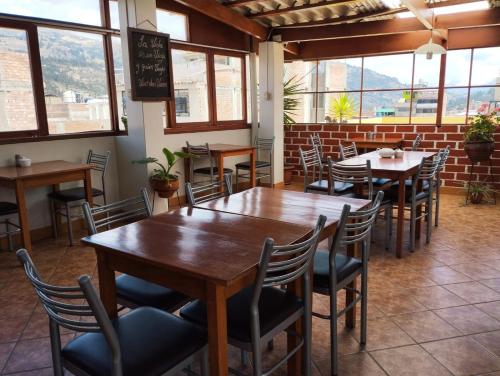 un ristorante con tavoli e sedie in legno e finestre di Hatun Wasi Huaraz a Huaraz