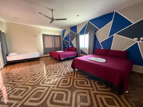 a bedroom with two beds and a blue wall at Casa pedregal in Cancún