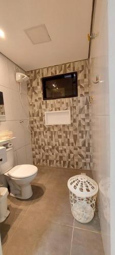 a bathroom with a toilet and a tv on the wall at Suit Confort in Porto Velho