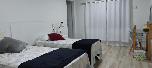 a bedroom with two beds and a table and a desk at Suit Confort in Porto Velho