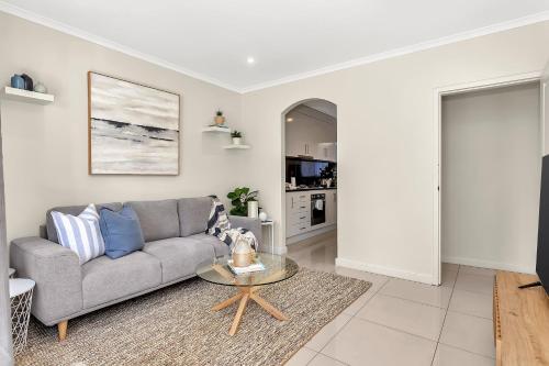 a living room with a couch and a table at Coastal Comfort with a Pool opposite Henley Beach in Adelaide