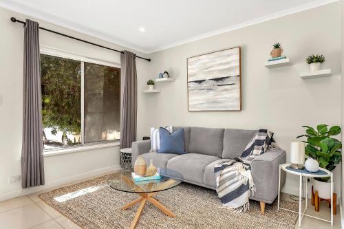 a living room with a couch and a table at Coastal Comfort with a Pool opposite Henley Beach in Adelaide