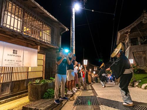 a group of people standing on a street at night at NIPPONIA Sado 佐渡相川 金山町 in Sado