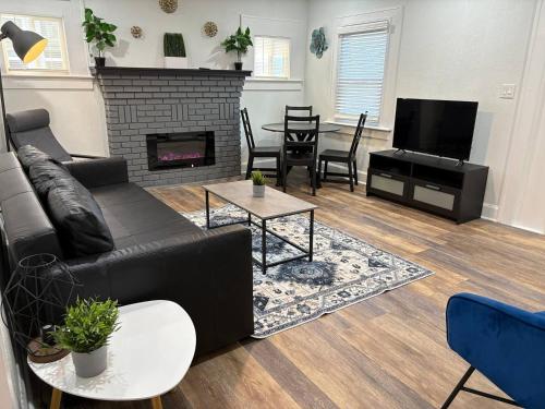 a living room with a black couch and a fireplace at Downtown Hideaway 1-Bedroom Bungalow in St. Petersburg