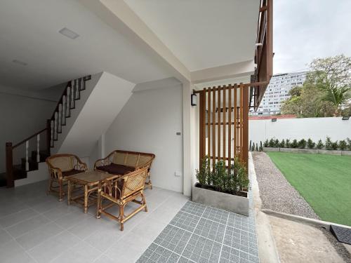 a porch with a table and chairs and a green field at Brown House Cha am in Cha Am