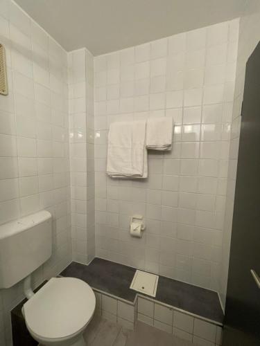 a white bathroom with a toilet and towels at Hotel Casa Andalucia in Hallbergmoos