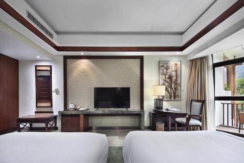 a bedroom with two beds and a flat screen tv at 广悦华阳朔河畔酒店 in Gaotian