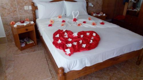 a bed with a heart made out of roses at Rising Sun Guesthouse in La Digue