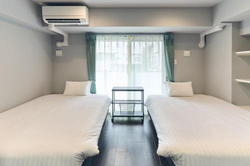 two beds in a room with a window at Vacation Rental Hotel TENMONKAN in Kagoshima