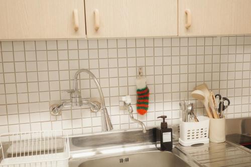 a kitchen counter with a sink and a tiled wall at Cozy 3-4 person accommodation in Suwon