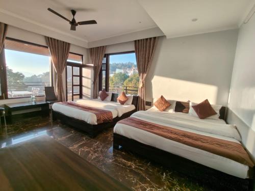 a hotel room with two beds and a large window at Leela In The Flavours of Nature in Dagshai