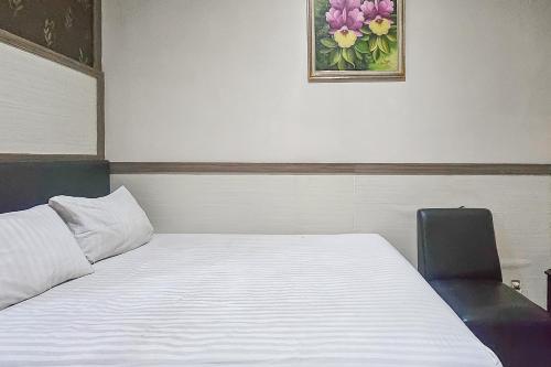 ein Schlafzimmer mit einem Bett, einem Stuhl und einem Bild in der Unterkunft Wisma Brata Mitra RedDoorz in Sukabumi