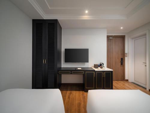 a bedroom with two beds and a desk with a television at Cloud 22Land hotel in Hanoi