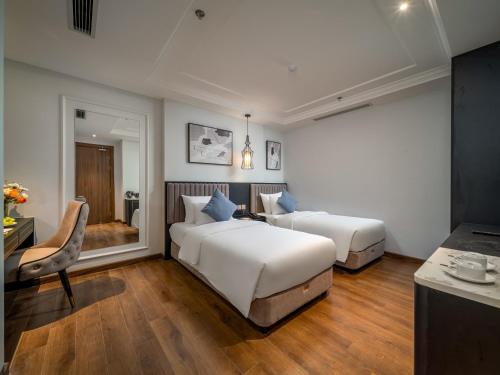 a bedroom with two beds and a desk and a chair at Cloud 22Land hotel in Hanoi