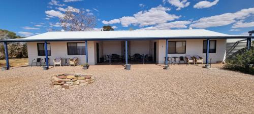 a white house with chairs and a fire pit at Windana Cottages in Hawker
