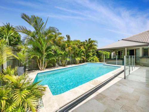 a swimming pool in front of a house with palm trees at Bokarina Pool House - Relaxed Coastal Living in Bokarina