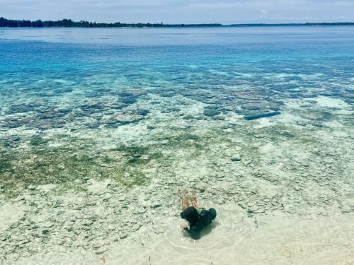 a person swimming in the water in the ocean at Fam Homestay in Fam