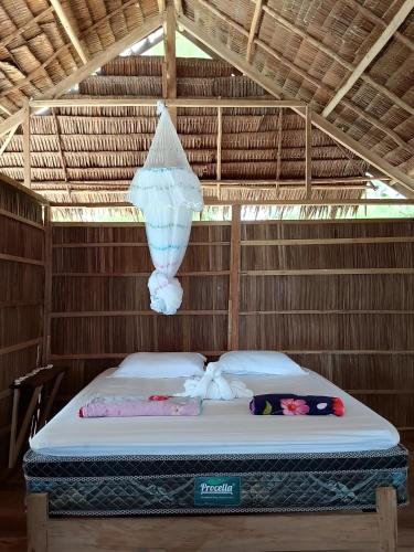 a bed in a straw hut with a chandelier at Fam Homestay in Fam