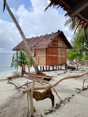 a shack on a beach with a tree branch on the sand at Fam Homestay in Fam