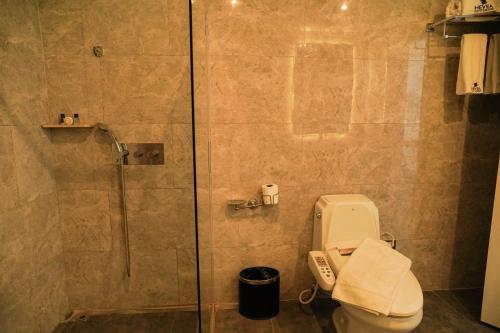 a bathroom with a toilet and a glass shower at Sunday Hevea Hotel and Resort in Angeles