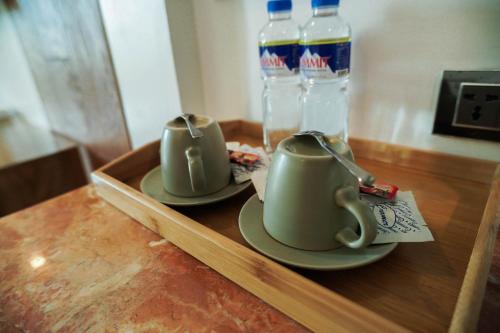 two teapots on a wooden tray with bottles of water at Sunday Hevea Hotel and Resort in Angeles