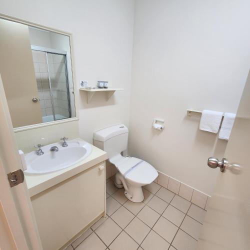a white bathroom with a toilet and a sink at Sun River Resort in Mildura