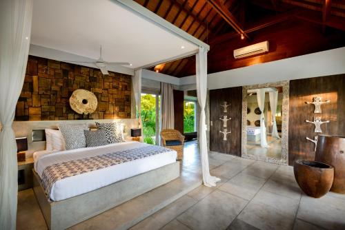 a bedroom with a large bed and a stone wall at Ipanema Villa Bali in Canggu