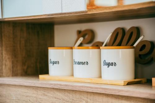 four coffee cups sitting on a shelf with utensils at Love, Lourdes Villa in Imus