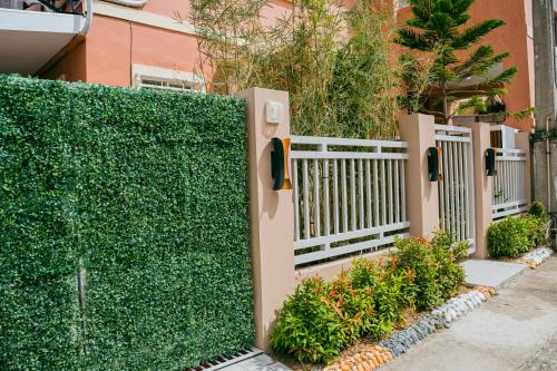 a privacy hedge with a white fence in front of a building at Love, Lourdes Villa in Imus