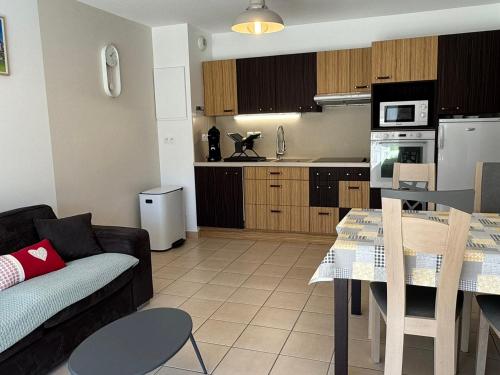 un salon et une cuisine avec un canapé et une table dans l'établissement Charmant 3 pièces avec terrasse près de la plage et parking sécurisé - FR-1-487-379, à Cabourg