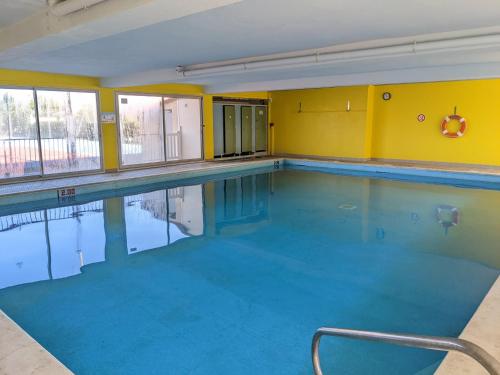 une piscine avec de l'eau bleue et des murs jaunes dans l'établissement Appartement T3 Moderne 5/6 Pers. avec Piscine et Parking - FR-1-797-63, à Port-la-Nouvelle
