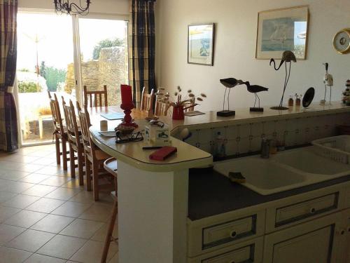 une cuisine avec un évier et une table avec des chaises dans l'établissement Grande maison familiale à Sarzeau, 12 personnes, vue mer - FR-1-639-142, à Sarzeau