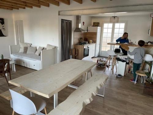 deux personnes dans un salon avec une table en bois dans l'établissement Maison au calme entre lac et bourg, à Biscarrosse