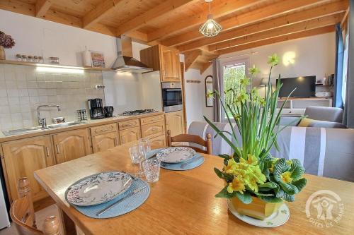 - une cuisine avec une table en bois, des assiettes et des fleurs dans l'établissement Ty bretz'l, à Paimpol