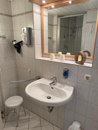 a bathroom with a sink and a mirror and a stool at Hotel Peters in Neuharlingersiel