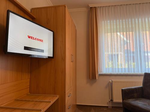 a flat screen tv in a living room with a window at Hotel Peters in Neuharlingersiel