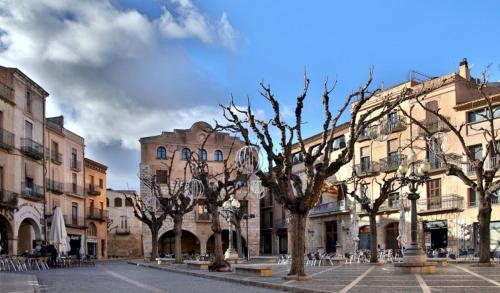 a group of trees in a courtyard in front of buildings at Pont Vell in Montblanc