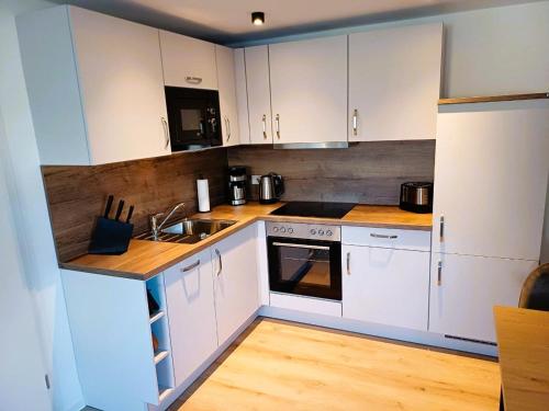 a kitchen with white cabinets and a wooden floor at Ferienwohnung Rosini in Hirschburg