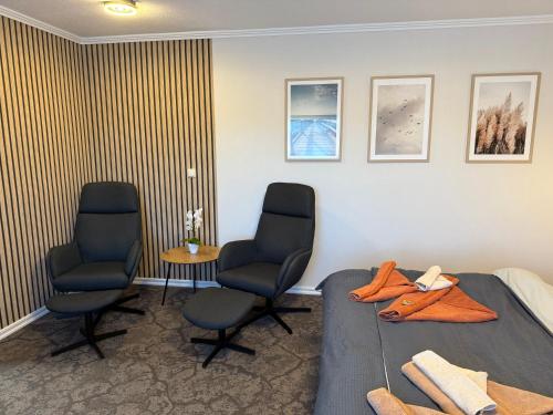 a room with two chairs and a bed and a table at Hotel Peters in Neuharlingersiel
