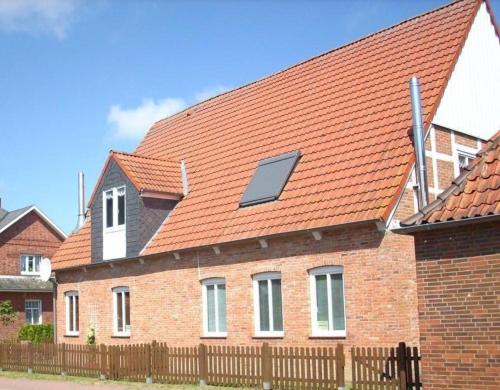 ein Haus mit einem orangenen Dach mit Sonnenkollektor darauf in der Unterkunft Ferienhaus "Oste-Anker" mit Sauna, Kaminofen und viel Platz für die Familie in ruhiger Lage in Oberndorf
