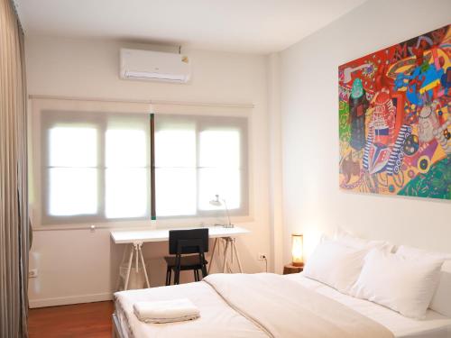 a bedroom with a bed and a desk and a window at Temple House Cottage in Lamphun