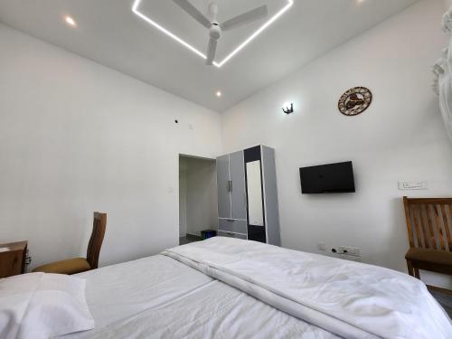 a bedroom with a white bed and a tv on the wall at Uthuppan's HolidayHome in Ūdumbanshola