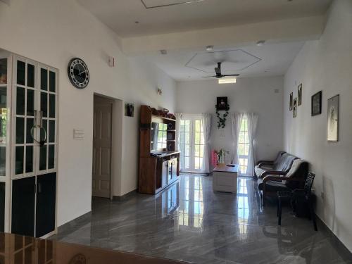 a living room with a couch and a clock on the wall at Uthuppan's HolidayHome in Ūdumbanshola