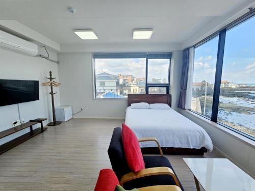 a bedroom with a bed and a large window at Here Now pension in Jeju