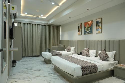 a hotel room with two beds and a television at Hotel M Town in Ahmedabad